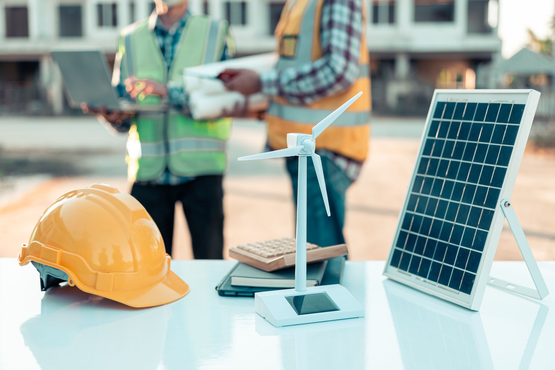 Two engineers work on wind turbine model components and discuss renewable energy sources of the solution with the computer. Wind turbine solar panel model to develop sustainable energy projects.