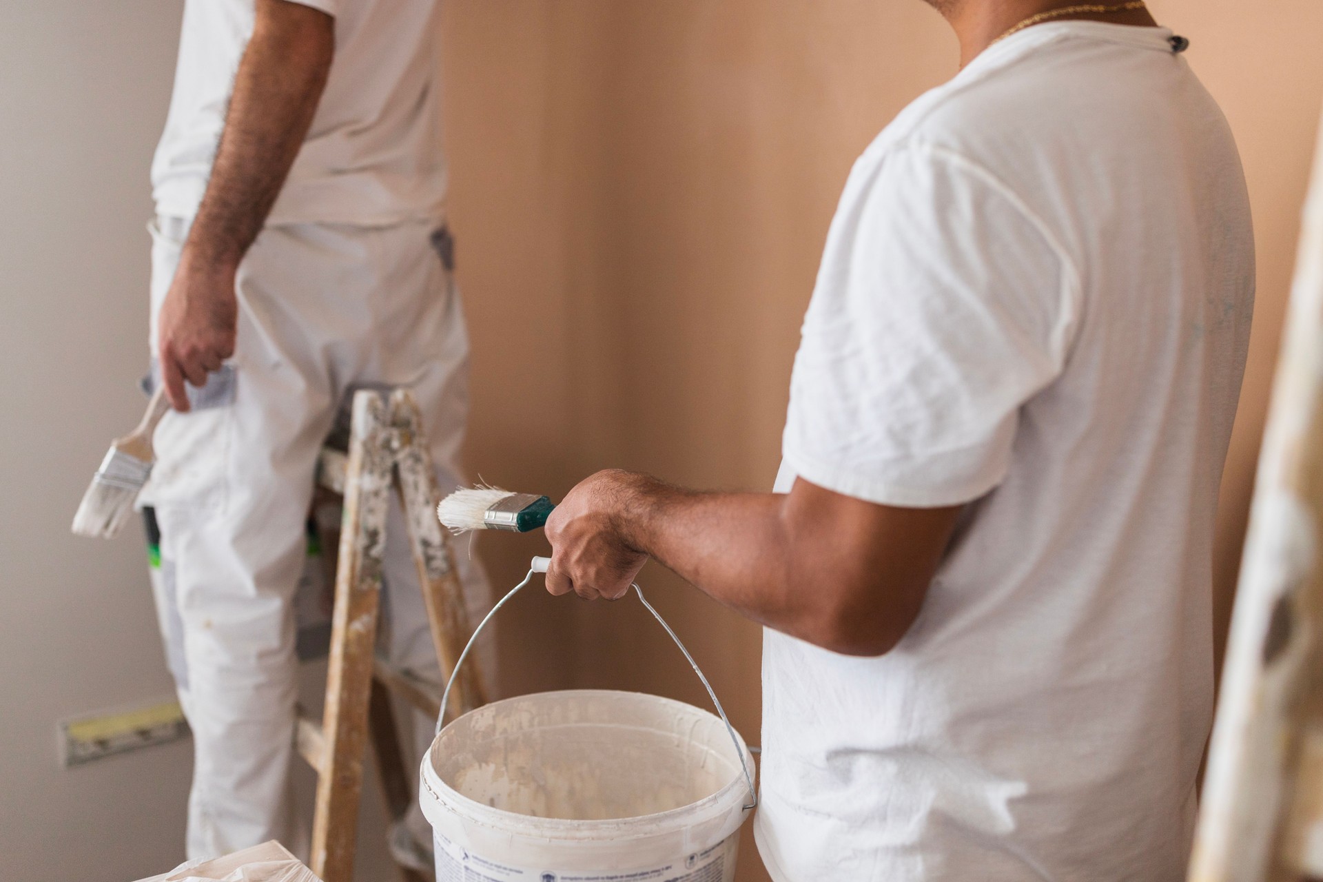 Home painter holding a bucket of white paint and a paint brush
