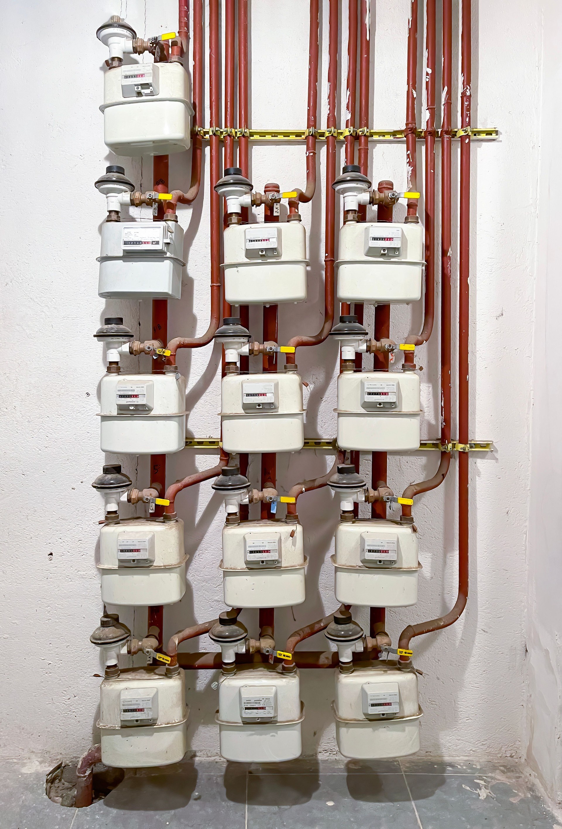 gas meter room of a residential building, gas meter consumption device with red pipes