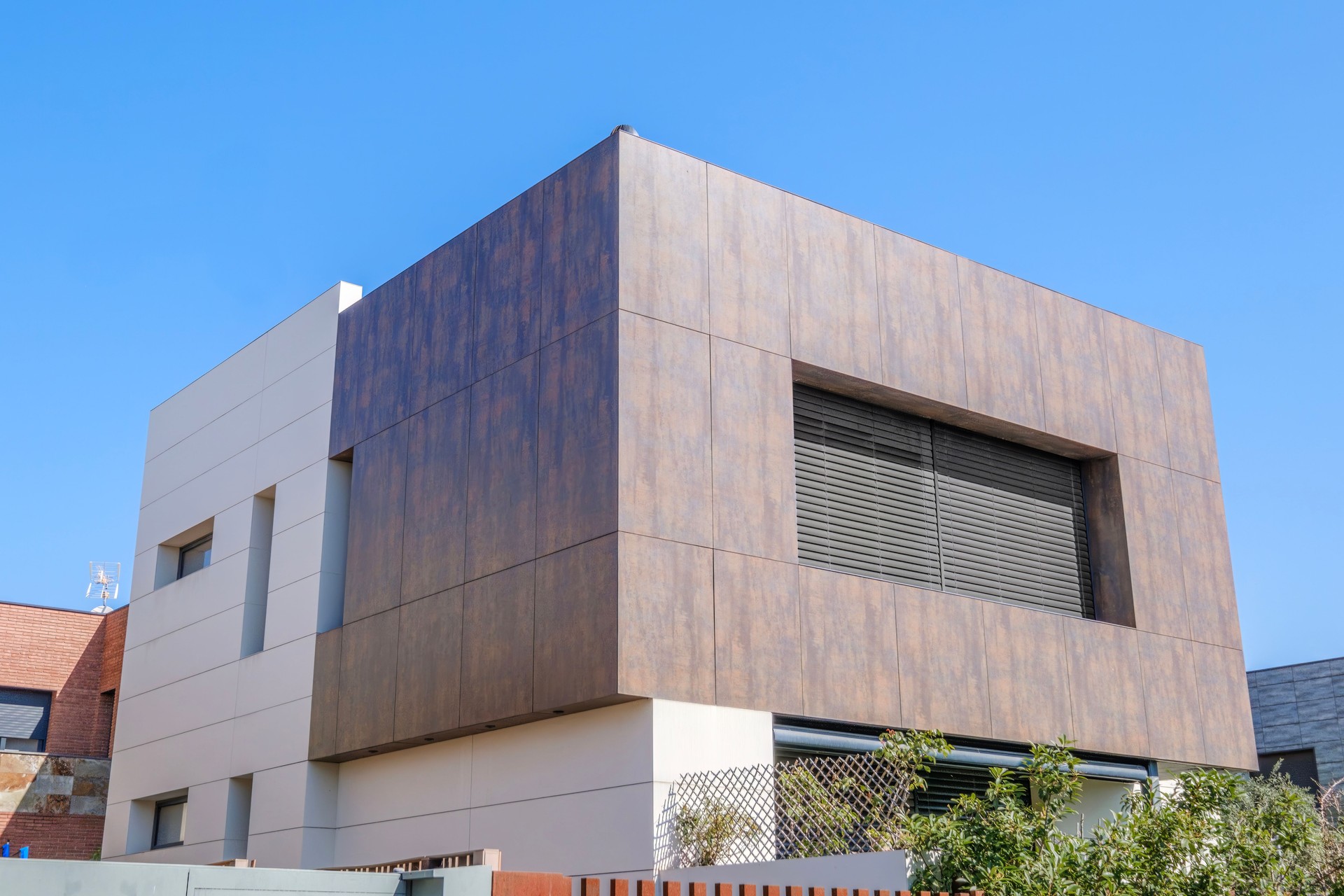 Striking Modern House With Wood Like Cladding And Minimalist Design Under Blue Sky. Contemporary architecture, luxury home, exterior view, building facade, stylish residence, real estate.